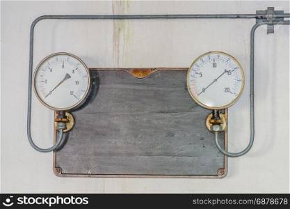 Two old pressure gauges on a metal plate made of cast iron with pressure supply lines from an old ice cream maker. Tex free space.