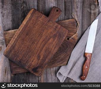 two old wooden cutting boards and a knife on a gray background, top view