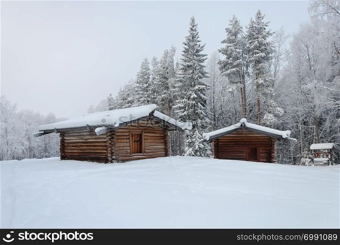 Two old wooden peasant barns in the northern open air museum Malye Korely near Arkhanglesk, Russia. Winter frosty day.
