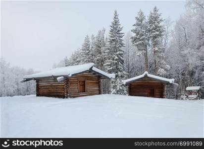 Two old wooden peasant barns in the northern open air museum Malye Korely near Arkhanglesk, Russia. Winter frosty day.
