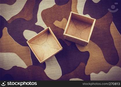 Two open cardboard boxes on a camouflage background