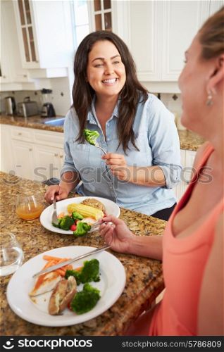 Two Overweight Women On Diet Eating Healthy Meal In Kitchen