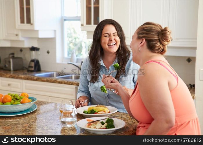 Two Overweight Women On Diet Eating Healthy Meal In Kitchen