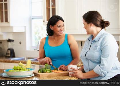 Two Overweight Women On Diet Preparing Vegetables in Kitchen
