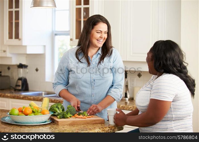 Two Overweight Women On Diet Preparing Vegetables in Kitchen