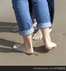 two pairs of feet close together on sand of beach of couple kissing