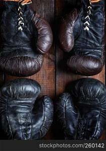 two pairs of leather old boxing gloves on wooden background, top view