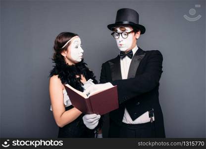 Two pantomime theater performers posing with book. Mime actor and actress performing. Two pantomime theater performers posing with book