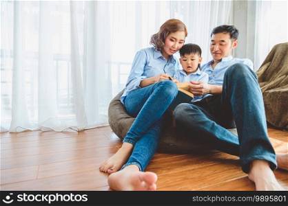 Two parents are teaching their sons to read in living room at home. People lifestyle and Education learning concept. State quarantine form Covid-19 theme. Study from home
