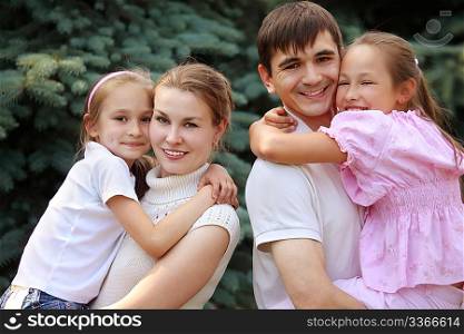 two parents hold children on hands on fir background