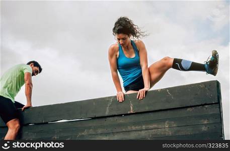 Two participants in an obstacle course climbing a wall