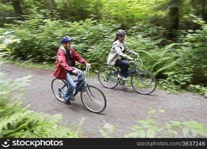 Two people biking in forest, elevated view, motion blur
