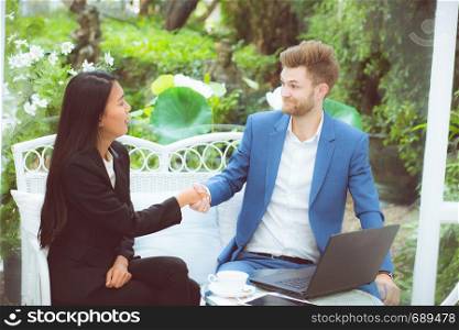 Two people happiness success business partner shaking hands in the office, businessman and businesswoman handshake successful with agreement, partnership concept.
