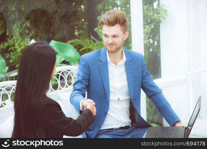 Two people happiness success business partner shaking hands in the office, businessman and businesswoman handshake successful with agreement, partnership concept.