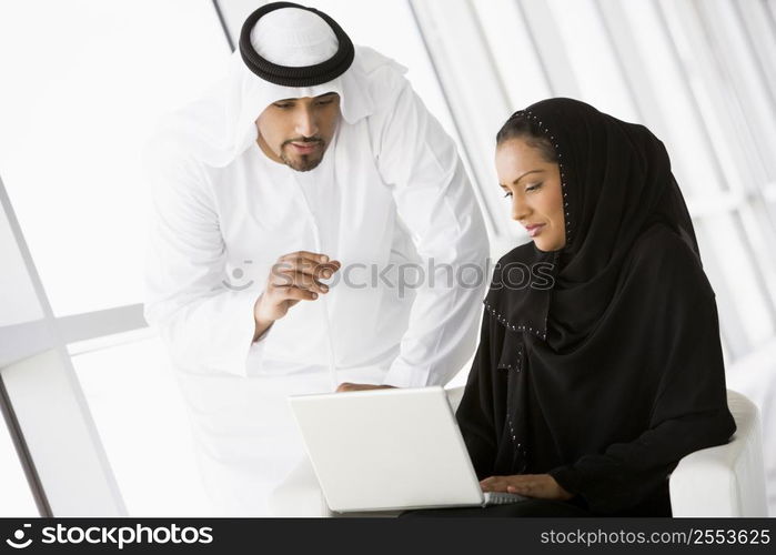 Two people indoors with laptop smiling (high key/selective focus)