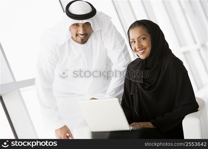 Two people indoors with laptop smiling (high key/selective focus)