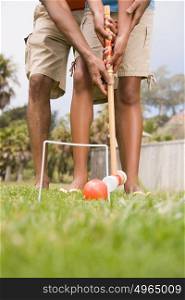 Two people playing croquet