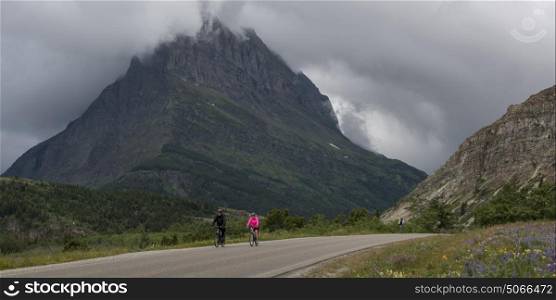 Two people riding bicycles on road, Many Glacier, Glacier National Park, Glacier County, Montana, USA