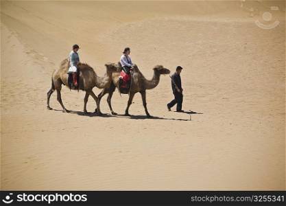 Two people riding camels in a desert, Kubuqi Desert, Inner Mongolia, China
