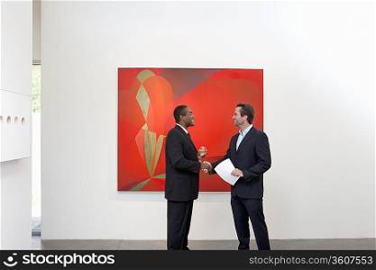 Two people shaking hands in front of wall painting