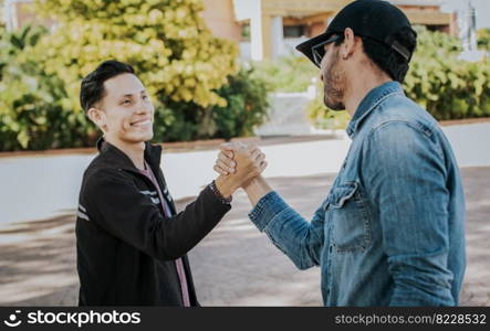 Two people shaking hands on the street. Two teenage friends shaking hands at each other outdoors. Concept of two friends greeting each other with handshake on the street.