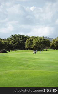 Two people standing near a golf cart in a golf course