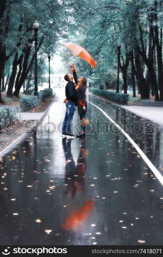 two people under an umbrella / a man and a woman are walking in a park with an umbrella, walking in the fall in the rain, an autumn umbrella