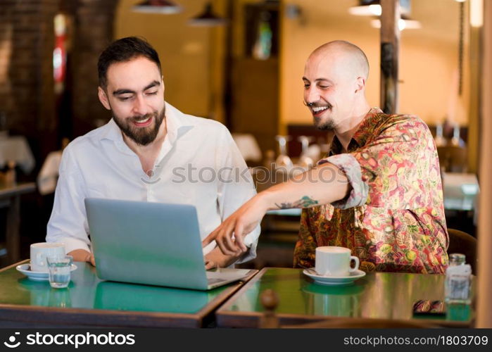 Two people using a laptop together during a meeting at a coffee shop.