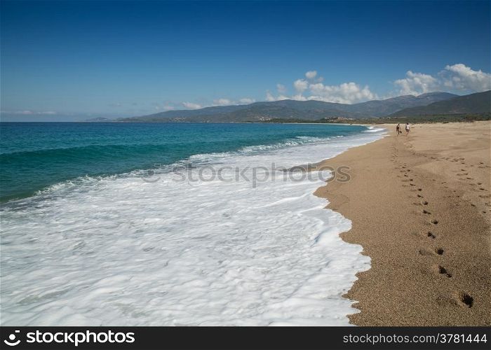 Two people walking along the Plage de Santana beach near Sagone in Corsica leaving footprints in the sand