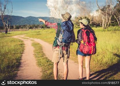 Two people walking on path in meadow field. Male and female traveler looking at attraction view point. Couples adventure at outdoors together. People and lifestyles concept. Trip and camping theme.