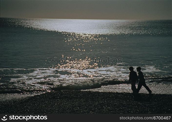 two people walking on the beach