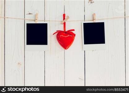 Two photo frame blank and red heart hanging on white wood with space. Valentine background.
