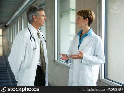 Two physicians having discussion in hospital corridor.