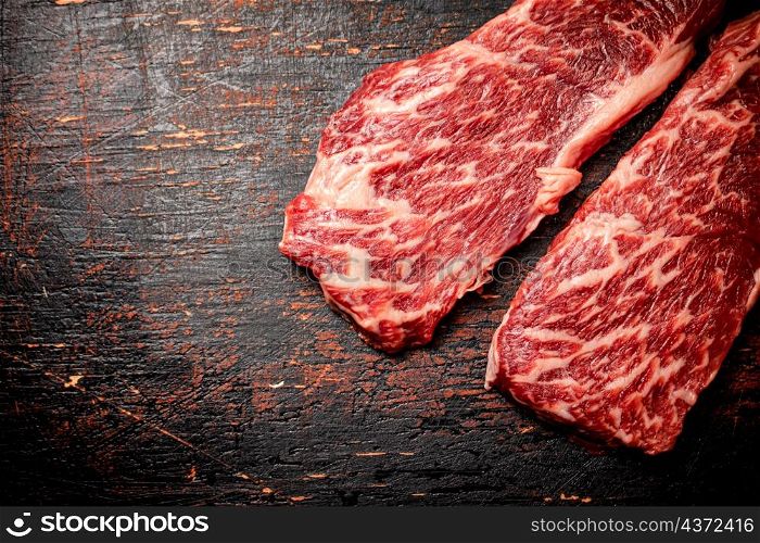Two pieces of fresh raw steak. On a rustic dark background. High quality photo. Two pieces of fresh raw steak.