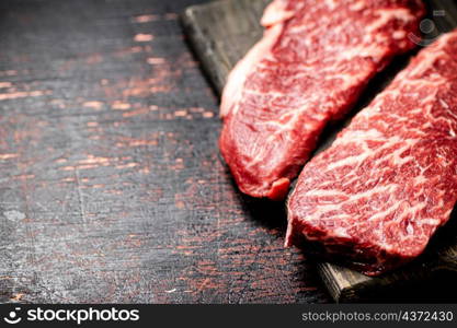 Two pieces of fresh raw steak. On a rustic dark background. High quality photo. Two pieces of fresh raw steak.