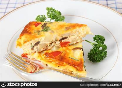 Two pieces of home-made spanish omelet on a plate with a fork and garnished with parsley