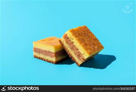Two pieces of homemade apple cake, minimalist on a blue table. Delicious layer cake with apple filling in bright light on a vibrant colored background