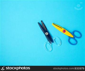 two pieces of plastic baby scissors for scrapbooking on a blue background, copxy space
