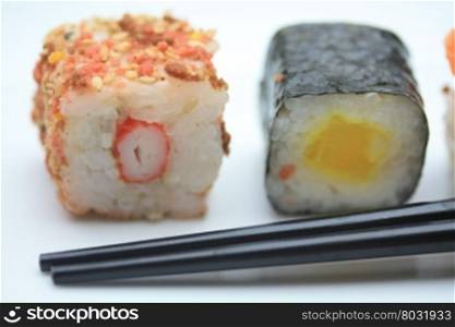 Two pieces of sushi sesame and rice and a traditional Makisushi, made from rice rolled in seaweed called Nori