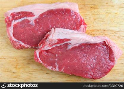 Two pieces of veal sirloin steak on a wooden chopping board