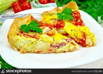 Two pieces pie of zucchini with tomatoes and eggs in a white plate on a napkin, parsley on a wooden boards background