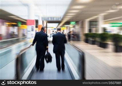 two pilots on a moving escalator