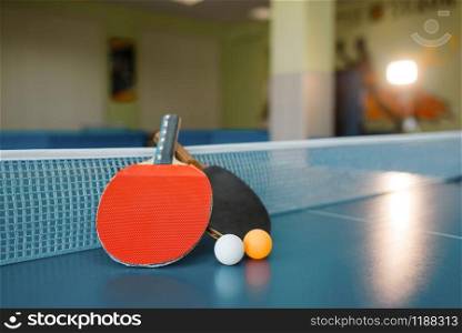 Two ping pong paddles on the table with net, nobody, closeup view. Table-tennis club, tennis concept. Two ping pong paddles on the table with net