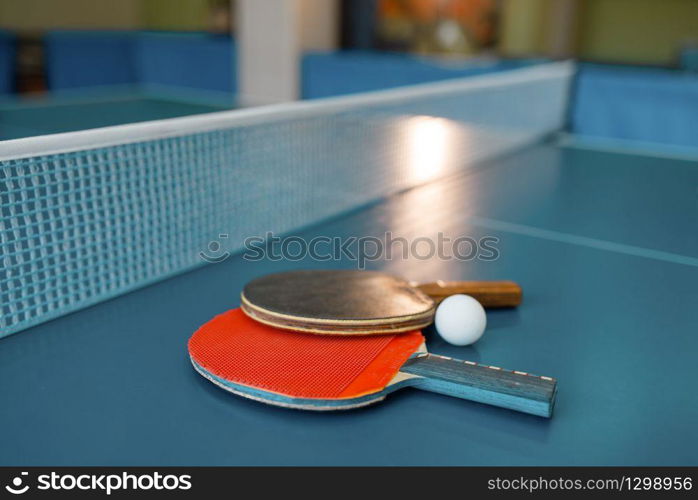 Two ping pong paddles on the table with net, nobody, closeup view. Table-tennis club, tennis concept