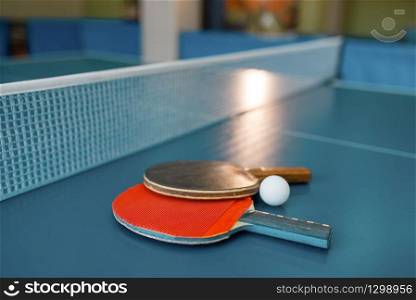 Two ping pong paddles on the table with net, nobody, closeup view. Table-tennis club, tennis concept