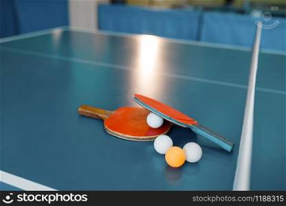 Two ping pong rackets and balls on game table with net, nobody, closeup view. Table-tennis club, tennis concept, ping-pong