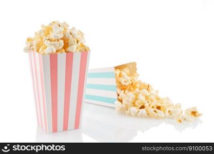Two pink and blue white striped carton buckets with tasty cheese popcorn, isolated on white background. Box with scattering of popcorn grains. Movies, cinema and entertainment concept.