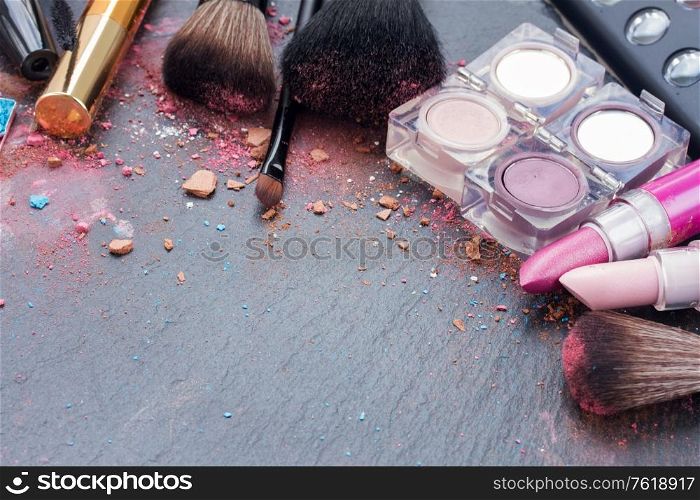 two pink lipsticks and eye shadows on black background with copy space. brushes on eye shadows palette