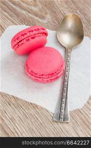 two pink strawberry  macaroons with spoon  on table