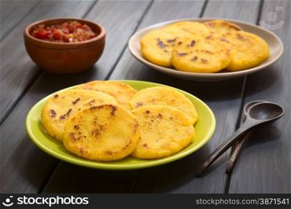 Two plates of arepas with Colombian hogao sauce (tomato and onion cooked) in the back. Arepas are made of yellow or white corn meal and are traditionally eaten in Colombia and Venezuela (Selective Focus, Focus on the first arepas)